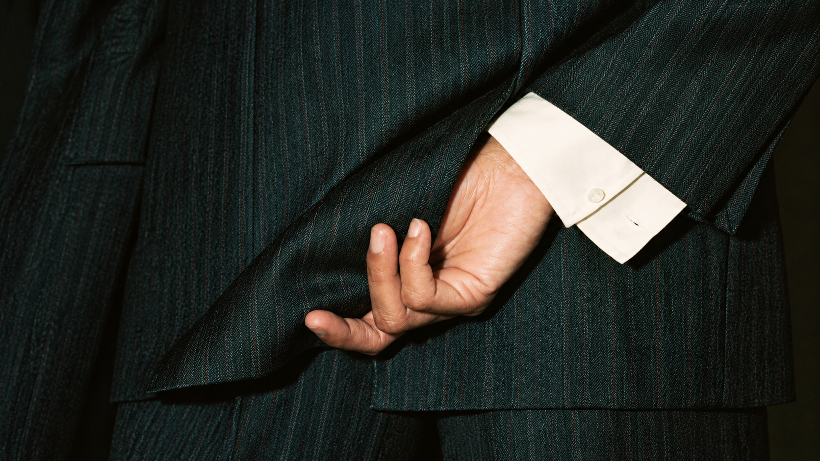 Dettaglio di un abito gessato con polsino della camicia